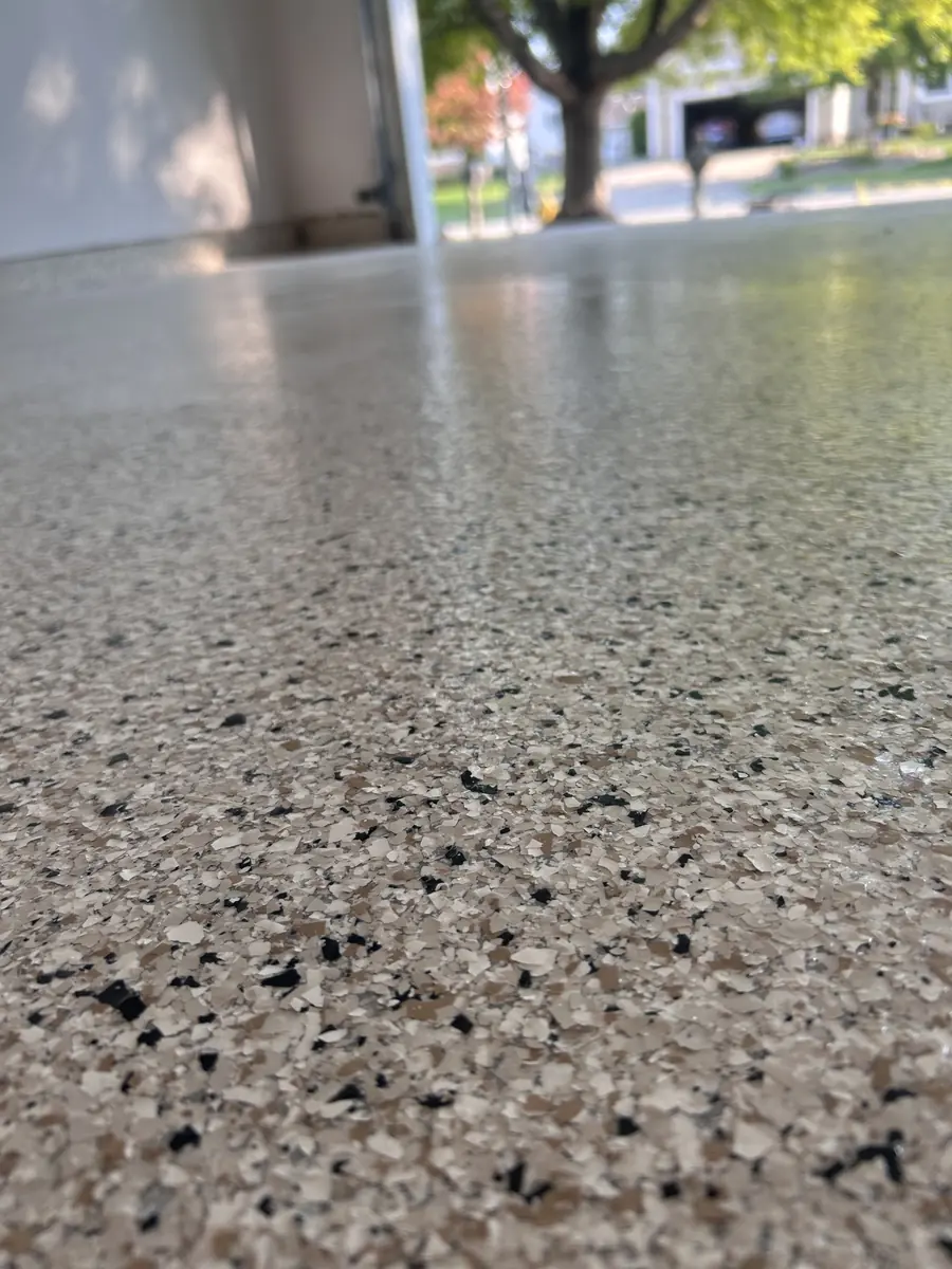 Close view of a full flake garage floor finish in Waukee, Iowa, vinyl chips sealed under a clear polyaspartic topcoat.