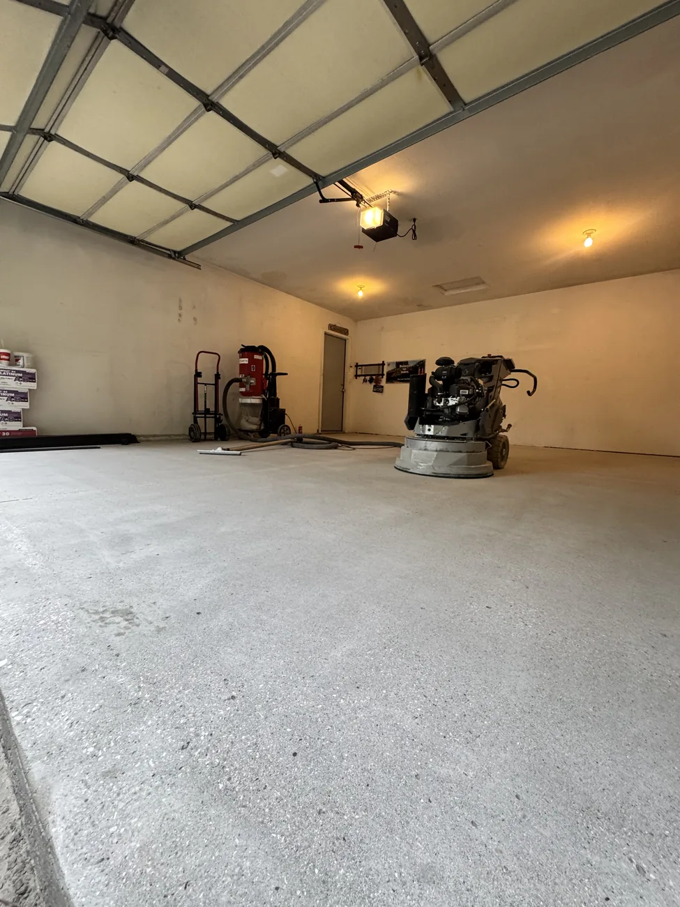 Diamond grinder and dust extractor parked on a freshly ground garage floor in Waukee, Iowa, the floor prepped wall to wall.